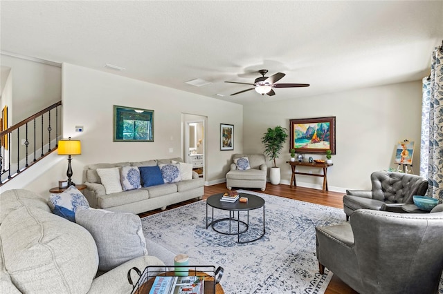 living room with a textured ceiling, ceiling fan, and wood-type flooring