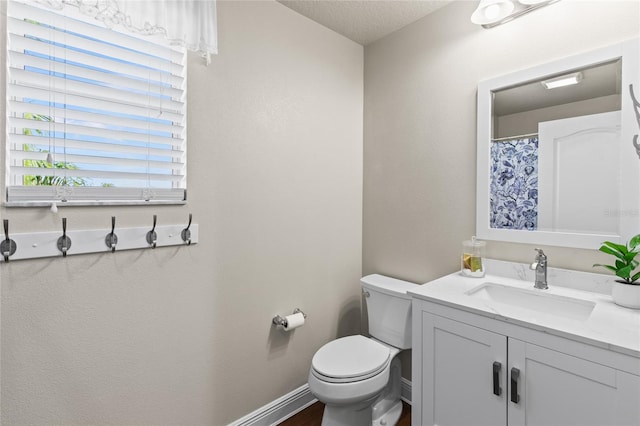 bathroom featuring toilet, vanity, and a textured ceiling