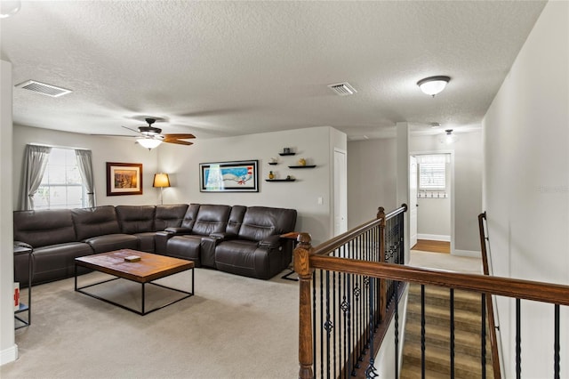 living room featuring a textured ceiling, a wealth of natural light, and light colored carpet