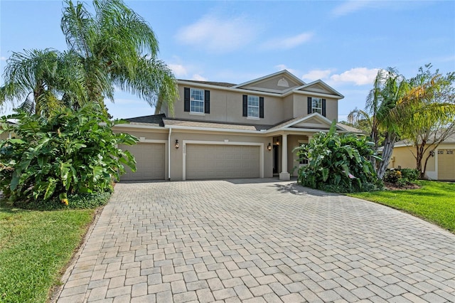 view of front of home with stucco siding, decorative driveway, and a garage