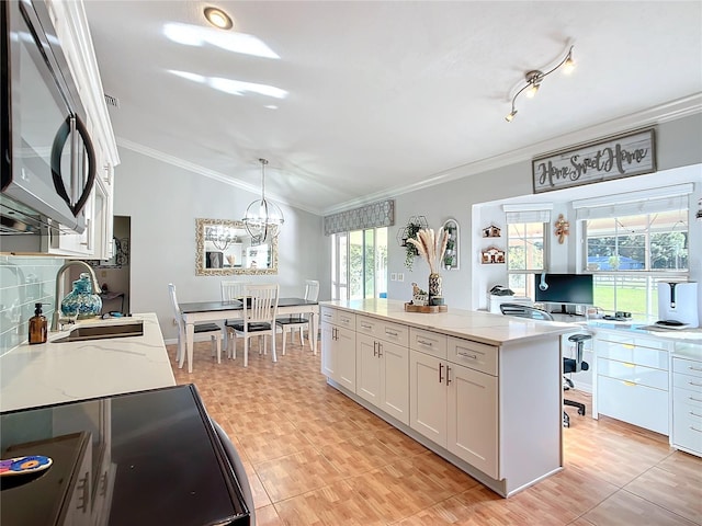 kitchen with light stone countertops, white cabinetry, pendant lighting, and sink