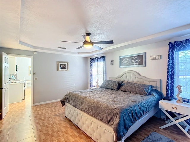 bedroom with ceiling fan, a textured ceiling, and a raised ceiling