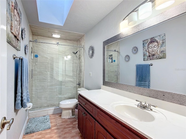 bathroom featuring tile patterned floors, vanity, a skylight, toilet, and a shower with shower door