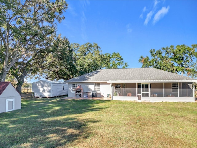 rear view of house featuring a patio area, a sunroom, a storage shed, and a lawn