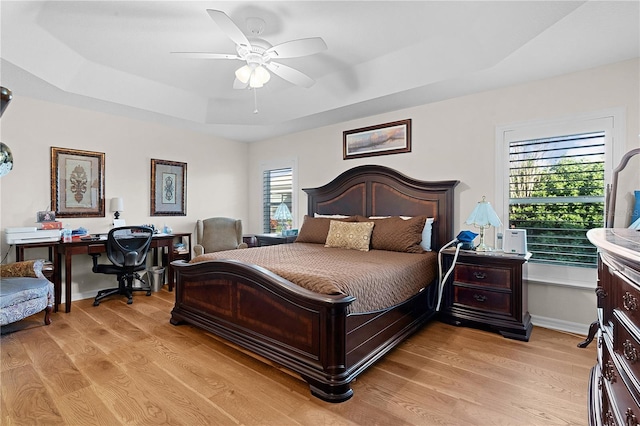 bedroom with a tray ceiling, light hardwood / wood-style flooring, and ceiling fan