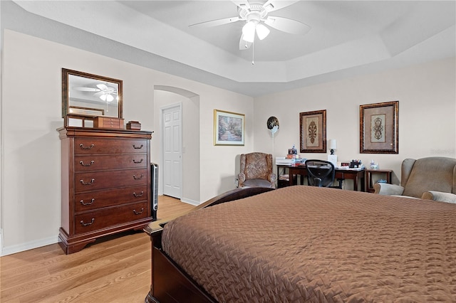 bedroom with a raised ceiling, light hardwood / wood-style flooring, and ceiling fan