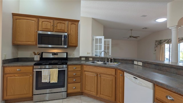 kitchen with sink, vaulted ceiling, ceiling fan, a textured ceiling, and appliances with stainless steel finishes