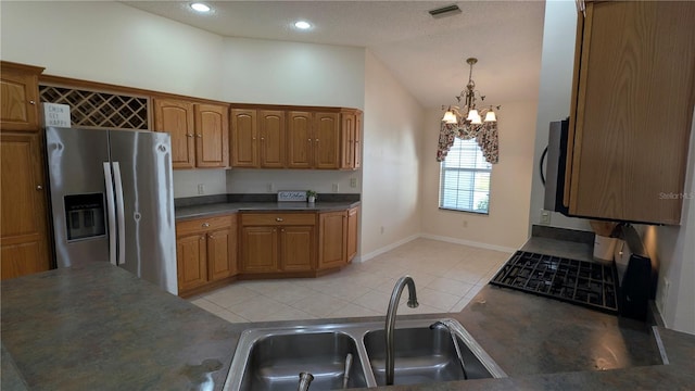 kitchen with sink, hanging light fixtures, a notable chandelier, vaulted ceiling, and appliances with stainless steel finishes