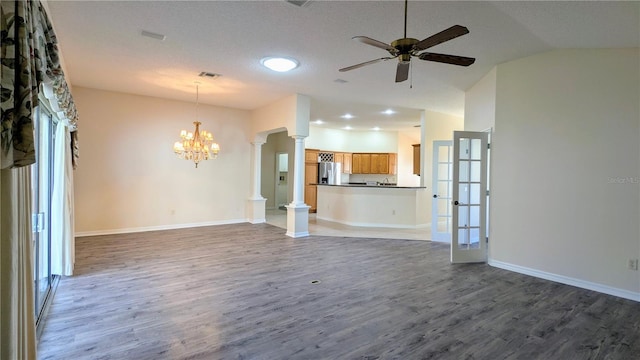 unfurnished living room with lofted ceiling, french doors, ceiling fan with notable chandelier, a textured ceiling, and dark hardwood / wood-style flooring