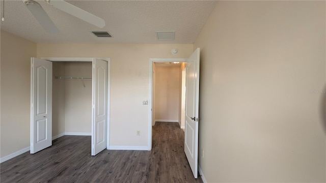 unfurnished bedroom with a textured ceiling, ceiling fan, a closet, and dark hardwood / wood-style floors