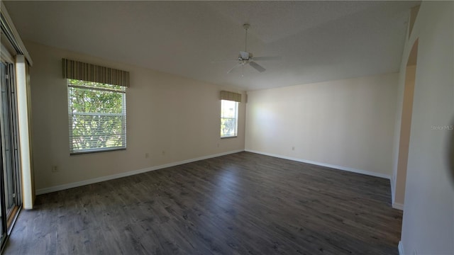 empty room with ceiling fan, dark hardwood / wood-style flooring, and a wealth of natural light