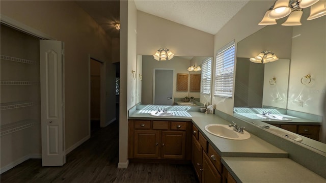 bathroom featuring vanity, a textured ceiling, vaulted ceiling, an inviting chandelier, and hardwood / wood-style floors