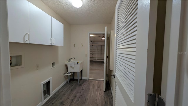 washroom with dark wood-type flooring, hookup for a washing machine, cabinets, and a textured ceiling