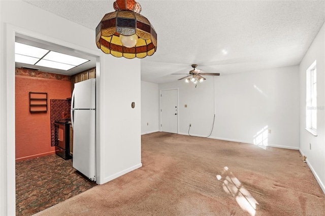 unfurnished living room with a textured ceiling, carpet flooring, and ceiling fan