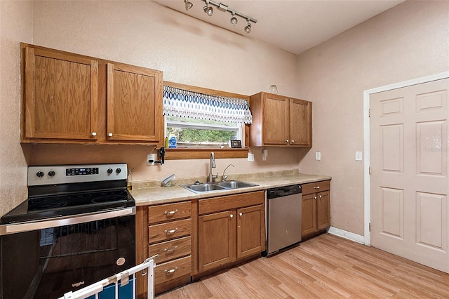 kitchen with sink, appliances with stainless steel finishes, rail lighting, and light wood-type flooring