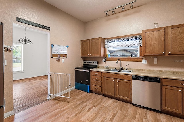 kitchen with pendant lighting, sink, light hardwood / wood-style flooring, and stainless steel appliances