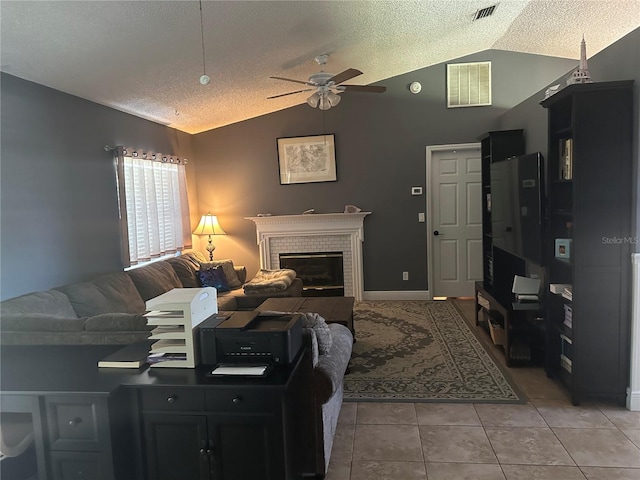 tiled living room featuring ceiling fan, a textured ceiling, lofted ceiling, and a brick fireplace