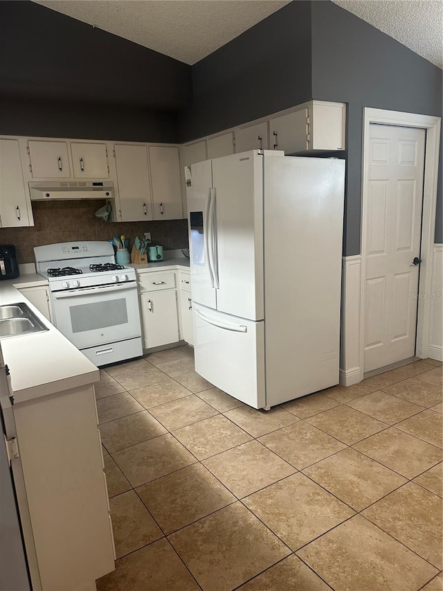 kitchen with tasteful backsplash, white appliances, lofted ceiling, white cabinets, and a textured ceiling