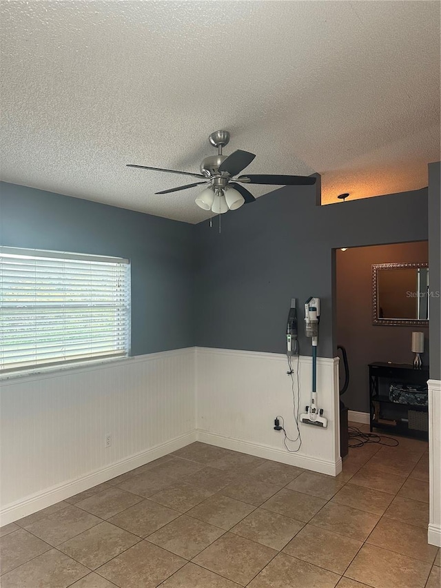 tiled spare room with ceiling fan and a textured ceiling