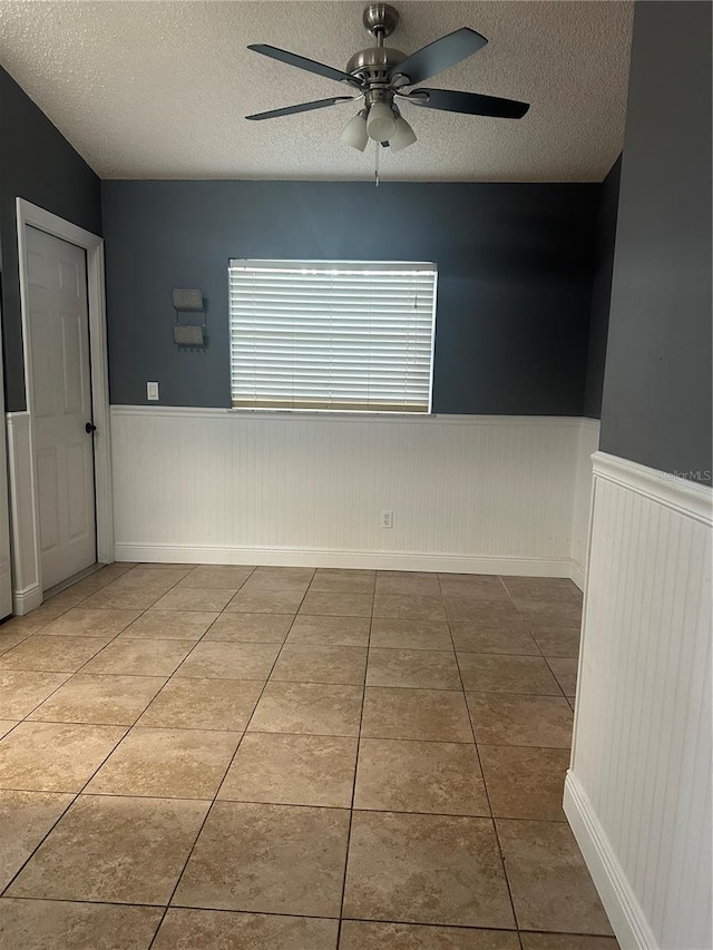 tiled spare room with ceiling fan and a textured ceiling