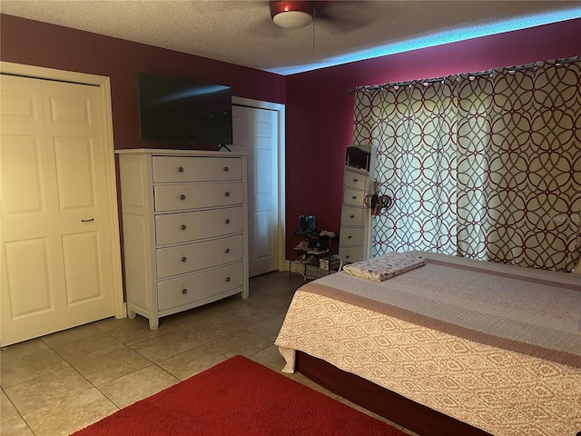 tiled bedroom featuring ceiling fan, a textured ceiling, and a closet