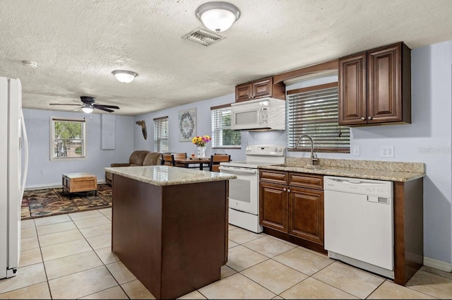 kitchen with a healthy amount of sunlight, white appliances, sink, and a textured ceiling