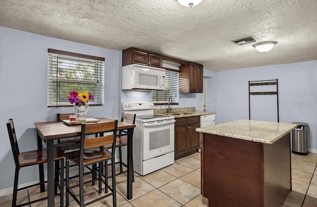 kitchen with white appliances, dark brown cabinets, sink, and a textured ceiling