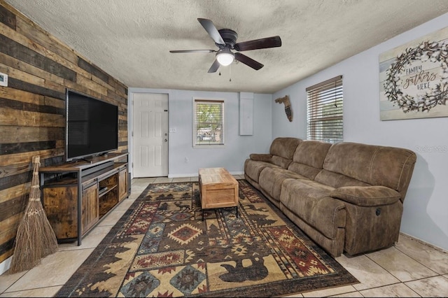 living room with ceiling fan, light tile patterned floors, and a textured ceiling