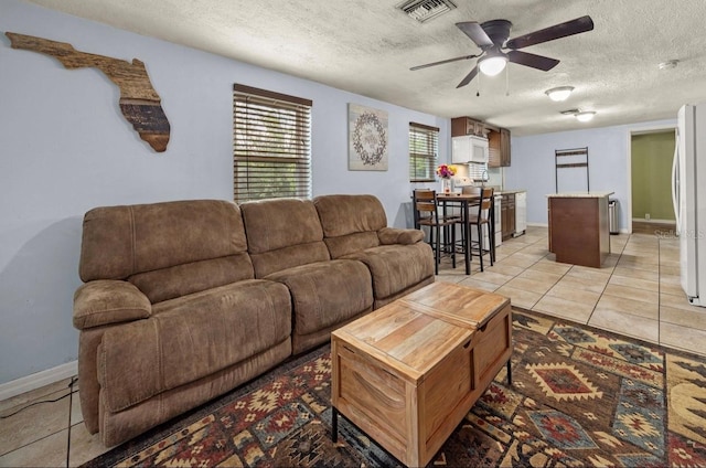 living room featuring ceiling fan, a textured ceiling, and light tile patterned flooring