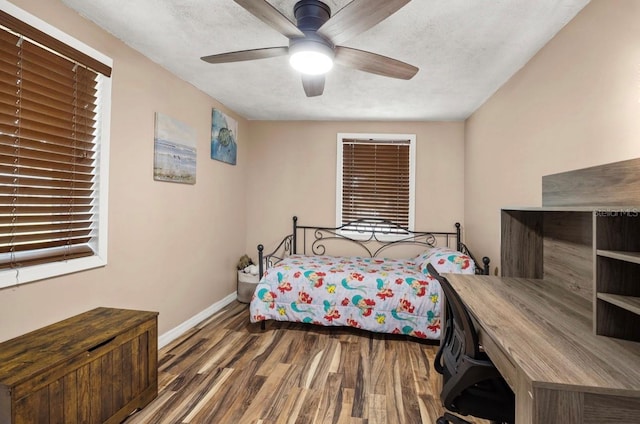 bedroom with ceiling fan, wood-type flooring, and a textured ceiling