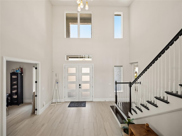 entryway featuring a towering ceiling, french doors, and light hardwood / wood-style floors