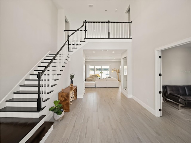 entryway featuring a towering ceiling and light wood-type flooring