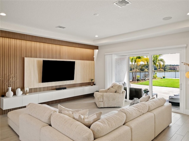 living room featuring wooden walls, a textured ceiling, and light hardwood / wood-style floors