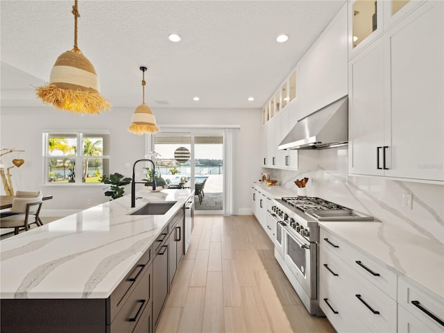 kitchen with white cabinets, stainless steel appliances, sink, and decorative light fixtures