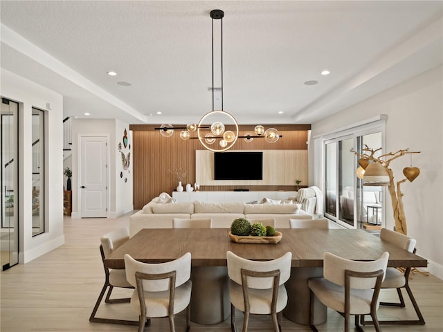 kitchen featuring hanging light fixtures, a kitchen breakfast bar, a textured ceiling, light hardwood / wood-style floors, and a notable chandelier