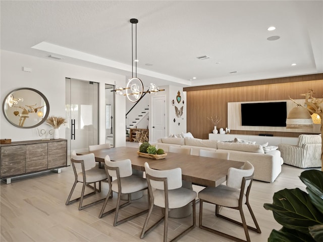 dining room with light hardwood / wood-style floors, a chandelier, and a tray ceiling