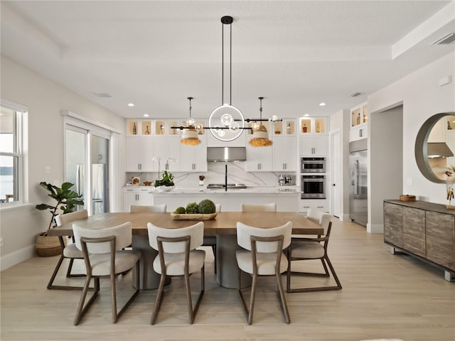 kitchen featuring appliances with stainless steel finishes, a large island, white cabinetry, and decorative light fixtures