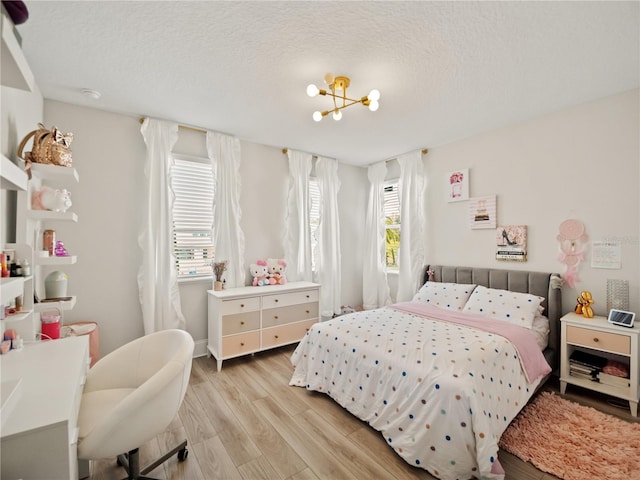 bedroom featuring a notable chandelier, a textured ceiling, and light wood-type flooring