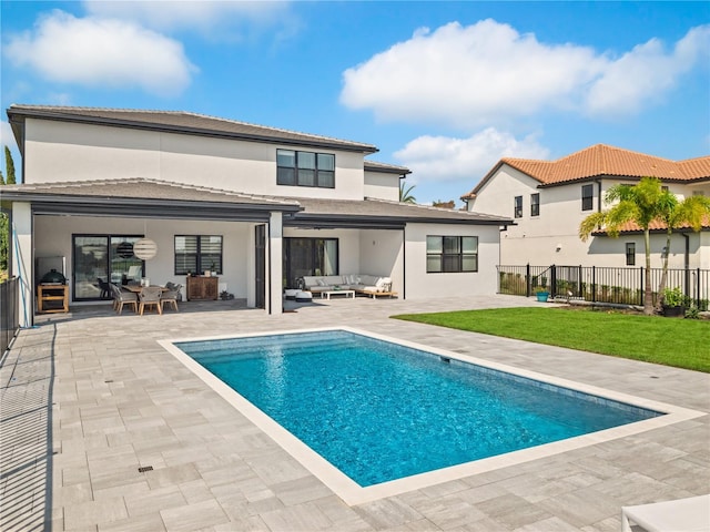 back of property featuring an outdoor living space, a fenced in pool, a patio area, and a lawn