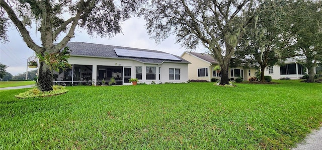 rear view of property with solar panels, a lawn, and a sunroom