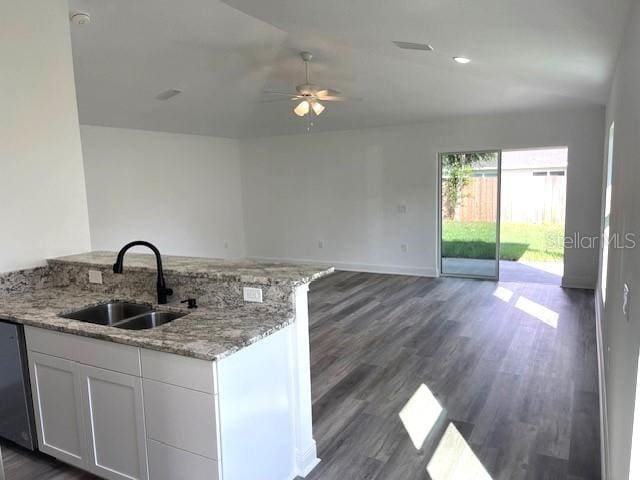 kitchen with light stone countertops, dark hardwood / wood-style floors, sink, and white cabinetry