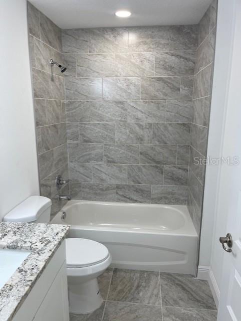 full bathroom with tiled shower / bath, vanity, and toilet