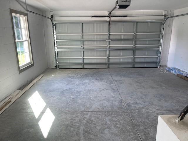 garage featuring concrete block wall and a garage door opener