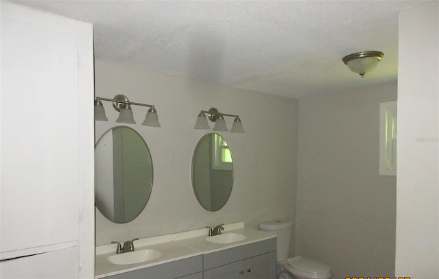 bathroom with vanity, toilet, and a textured ceiling