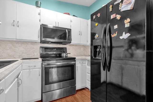 kitchen featuring white cabinets, light hardwood / wood-style flooring, stainless steel appliances, and backsplash