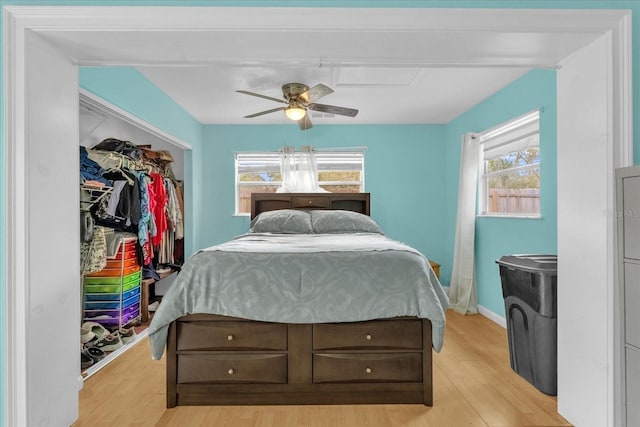 bedroom featuring a closet, light hardwood / wood-style floors, multiple windows, and ceiling fan