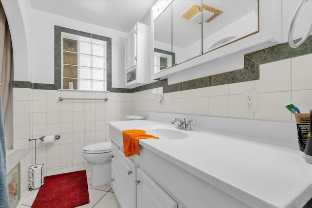 bathroom with tile walls, vanity, toilet, and tile patterned floors