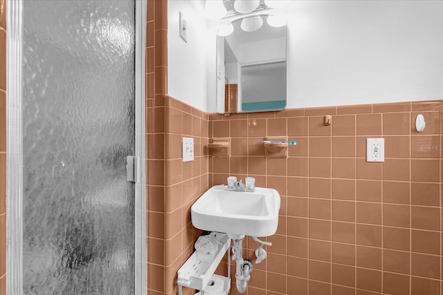 bathroom with a shower with door and tile walls