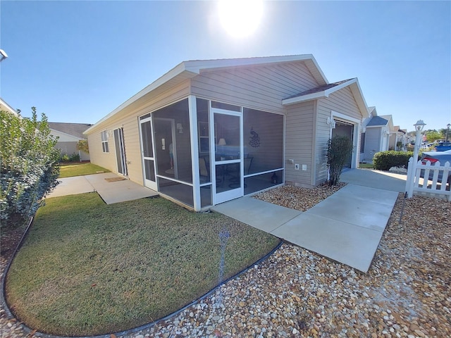 view of side of home featuring a yard, a sunroom, and a garage