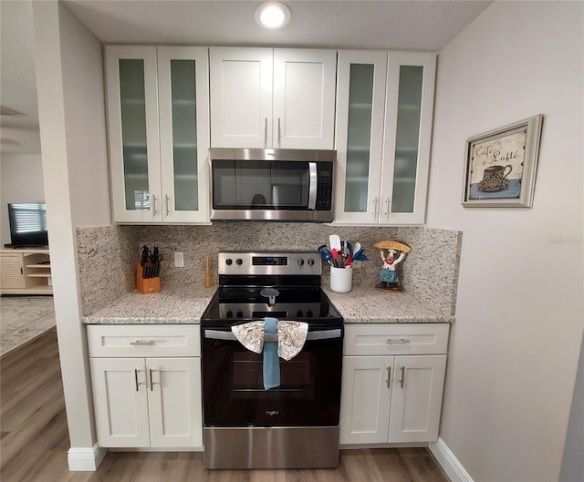 kitchen featuring light stone countertops, appliances with stainless steel finishes, white cabinets, and light hardwood / wood-style floors